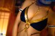 A woman in a blue and gold bikini with a gold chain around her neck.