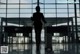 A woman walking through an airport with a suitcase.