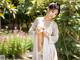 A woman in a white kimono posing in a garden.