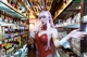 A woman in a bunny costume standing in front of a shelf of beer.