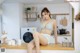 A woman sitting on top of a counter in a kitchen.