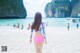 A woman in a pink bikini walking on a beach.