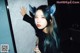 A woman with blue hair wearing a cat ears headband.
