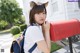 A woman in a school uniform holding a red mailbox.