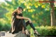 A woman sitting on a stone ledge in a park.