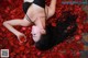 A woman laying on a bed of red rose petals.