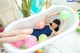 A woman laying in a bathtub with balloons.