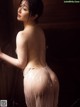 A naked woman standing in front of a curtain.