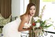 A woman in a white dress holding a vase of flowers.