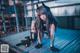 A woman in a black outfit crouching down on a metal platform.