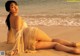 A woman in a white dress laying on the beach.