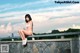 A woman in a white bikini sitting on a stone wall.