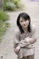 A woman sitting on a dirt road in a dress.