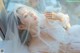 A woman in a white lingerie laying on a window sill.