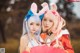 Two young women dressed in bunny ears pose for a picture.